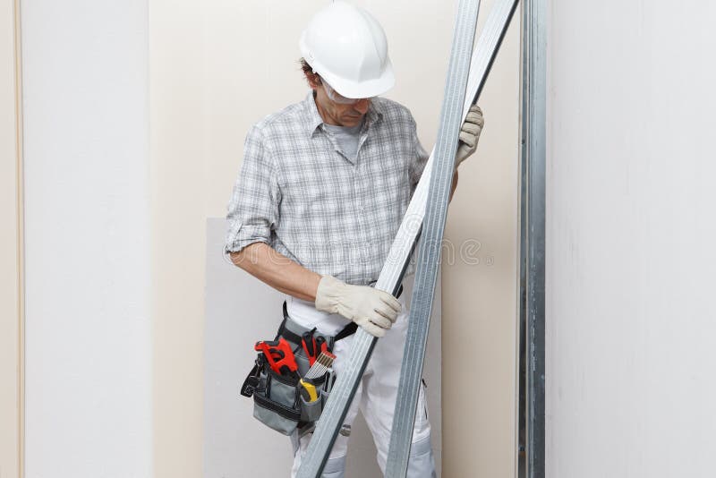 Bauarbeiter oder Putzer mit Trockenbau Metallprofile in der Nähe Gipskarton weiße Wand in Baustelle. strahlendes Weiß lizenzfreie stockfotos