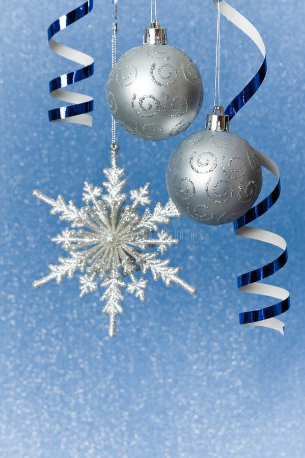 Silver Christmas baubles, snowflake and ribbon ornament on blue background of defocused lights. Shallow DOF. Silver Christmas baubles, snowflake and ribbon ornament on blue background of defocused lights. Shallow DOF.