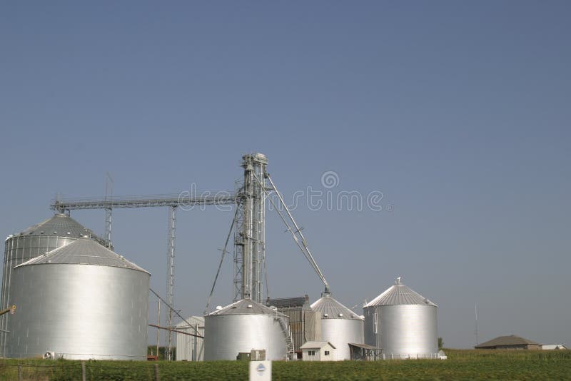 Silver metal farm silos on a farm against a blue sky. Silver metal farm silos on a farm against a blue sky