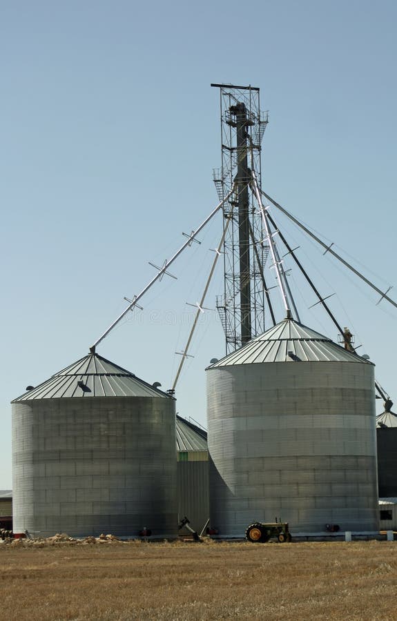 A tractor stands in front of grain silos on a Colorado farm. The silos can be used for different types of grains and corn. A tractor stands in front of grain silos on a Colorado farm. The silos can be used for different types of grains and corn.