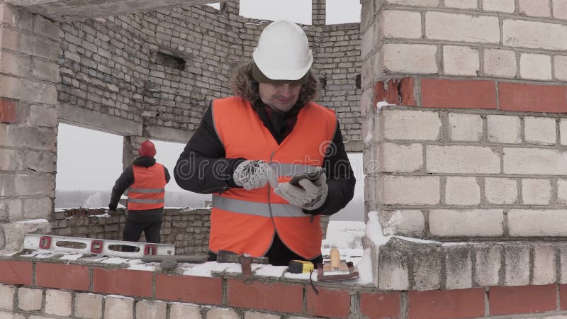 Bauingenieur, der am intelligenten Telefon spricht und in unfertiges Gebäude geht stock footage