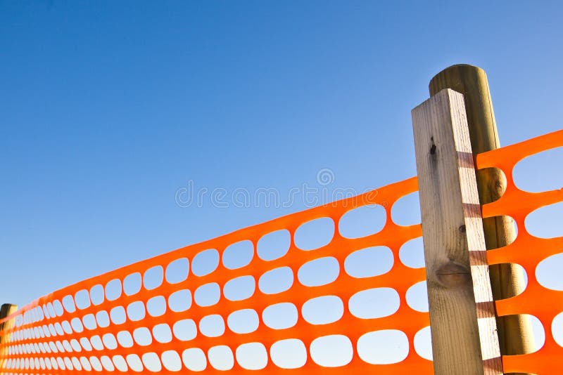 Baustelle mit orange Gitter der Sicherheit gegen einen blauen Himmel stockfotografie Baustelle mit orange Gitter der Sicherheit gegen einen blauen Himmel stockfotografie