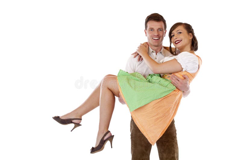 Bavarian man carries woman with dirndl on hands.