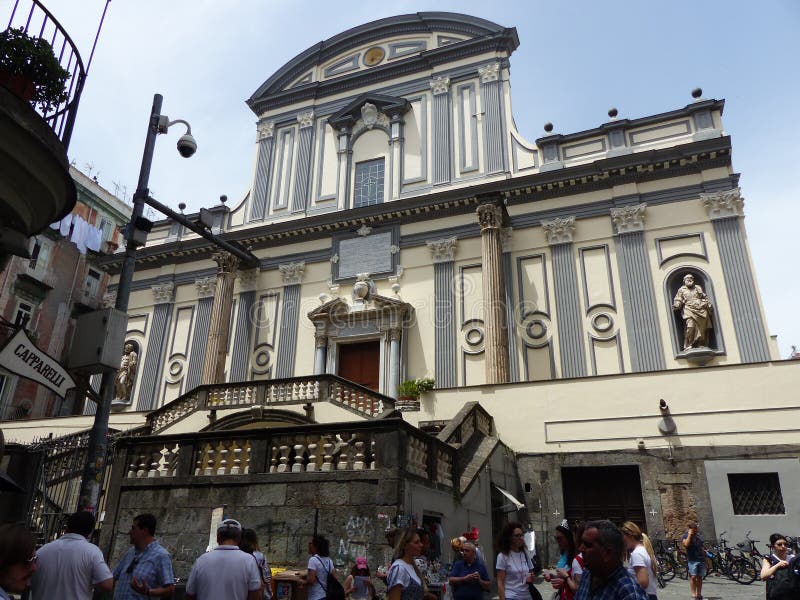 Basilic of San Paolo Maggiore in the historic center of Naples, Italy. Springtime and holidaytime. Blue clear sky. Sunny day. Bicolored facade with niches with standing statues inside. Grey and white. Baroque style. Stairways tor reach it. Seen from below. A lot of people on the street. See Naples and died. Architecture, culture, heritage, art, story and religion. Basilic of San Paolo Maggiore in the historic center of Naples, Italy. Springtime and holidaytime. Blue clear sky. Sunny day. Bicolored facade with niches with standing statues inside. Grey and white. Baroque style. Stairways tor reach it. Seen from below. A lot of people on the street. See Naples and died. Architecture, culture, heritage, art, story and religion.