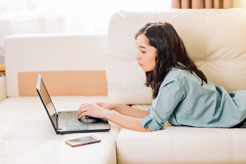 Bbeautiful kvinna som hemma använder bärbar datordatoren på soffan arkivbilder Bbeautiful kvinna som hemma använder bärbar datordatoren på soffan arkivbilder