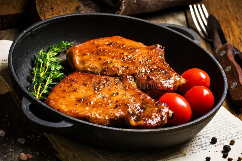 Alla griglia maiale braciole dolce Miele smalto, serviamo griglia ferro padella fresco timo, segale pane un ciliegia pomodori, da vicino.