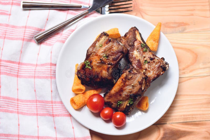 Bbq pork ribs grilled with tomatoes herbs and spices on plate served on wooden table - Roasted barbecue pork spare rib sliced stock photography Bbq pork ribs grilled with tomatoes herbs and spices on plate served on wooden table - Roasted barbecue pork spare rib sliced stock photography
