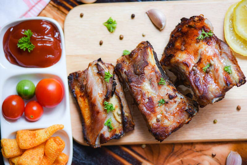 Bbq pork ribs grilled with tomatoes ketchup and herbs spices served on the wooden cutting board on table - Roasted barbecue pork stock images Bbq pork ribs grilled with tomatoes ketchup and herbs spices served on the wooden cutting board on table - Roasted barbecue pork stock images