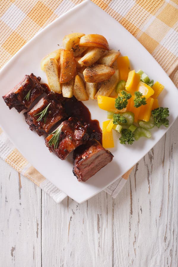 BBQ Pork Ribs with Vegetables on a Plate. Vertical Top View Stock Photo