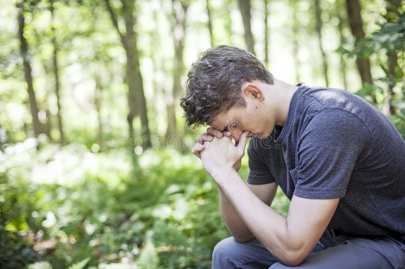 A young man praying in nature. A young man praying in nature