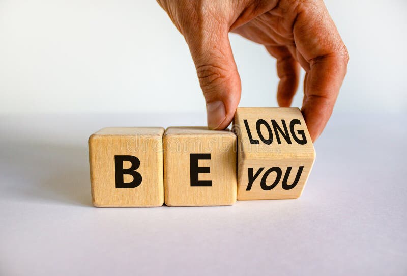 Be you, belong symbol. Businessman hand turns a cube and changes words `be you` to `belong`. Beautiful white background. Busin