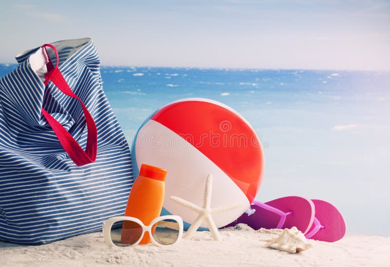 Beach bag, sun glasses and flip flops on a tropical beach