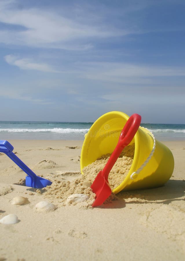 Beach bucket and spades. A child's beach bucket and spades. Primary colours of red, yellow, blue royalty free stock photos