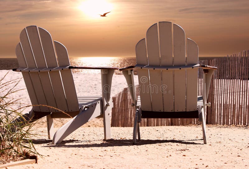 Sillas sobre el Playa cómo puestas de sol gaviota volador a través de.