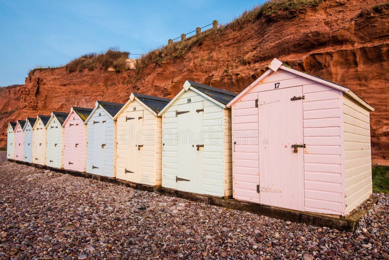 Beach hut row in pastel colors, red rock cliff background