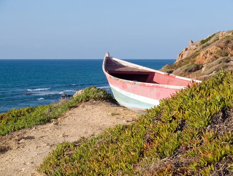 Beach coast landscape - small colorful skiff dory boat on the cliff. Beach coast landscape - small colorful skiff dory boat on the cliff