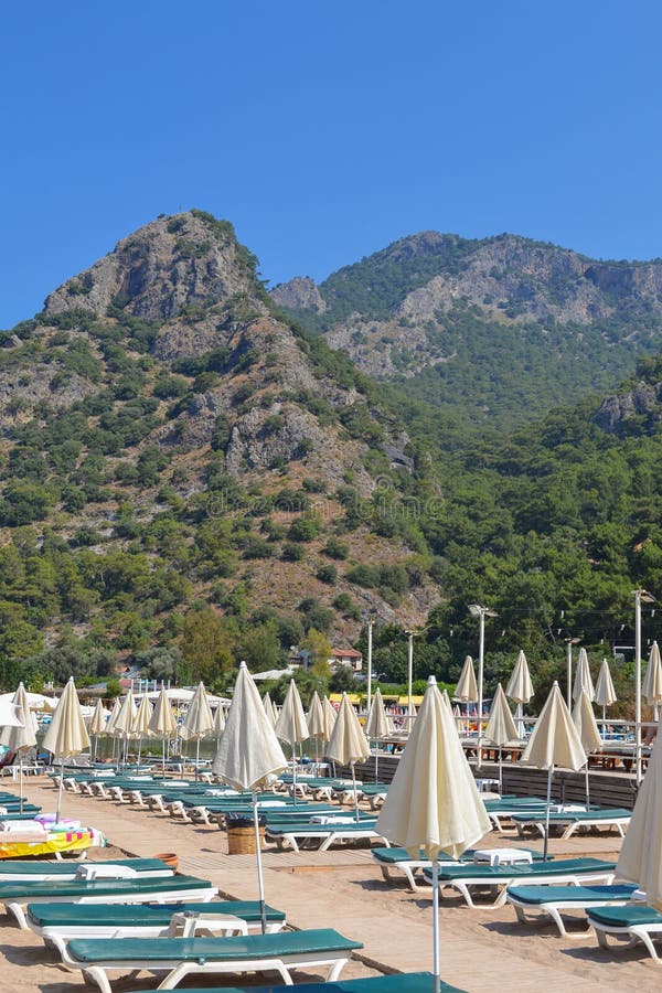 Beach with sun beds and closed umbrellas in the background of the surrounding mountains Oludeniz, Turkey. royalty free stock images Beach with sun beds and closed umbrellas in the background of the surrounding mountains Oludeniz, Turkey. royalty free stock images