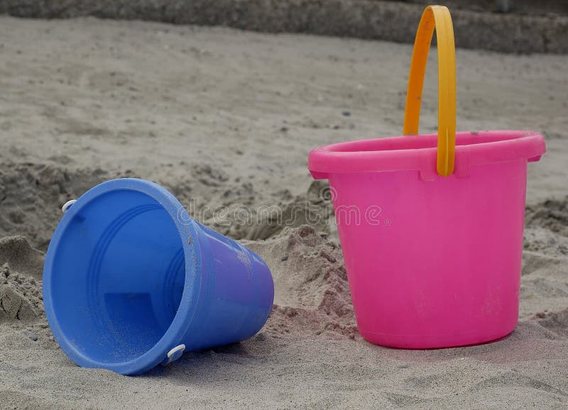 Modré a ružové plastové vedierka, detské hračky na pláži.