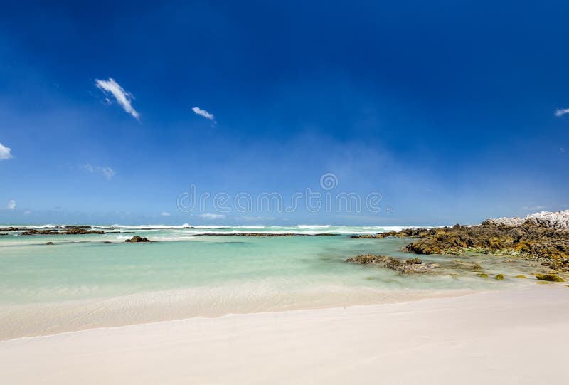 Beach view with white sand, rocks and crystal clear water at Brandfontein - Rietfontein Nature Reserve near Cape Agulhas