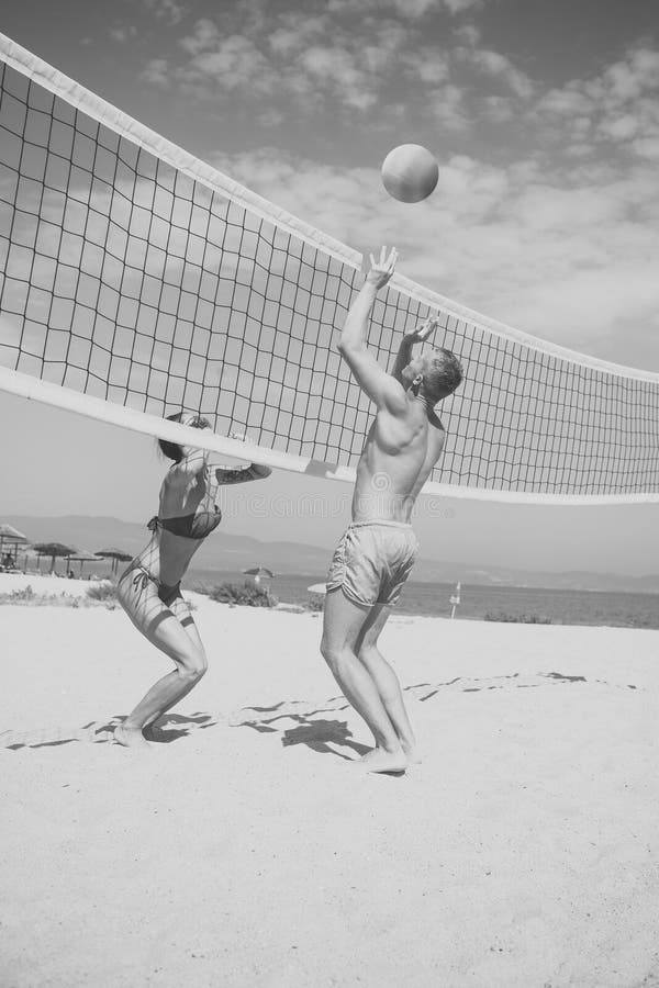 Beach volleyball concept. Couple have fun playing volleyball. Young sporty active couple beat off volley ball, play game on summer day. Woman and men fit, strong, healthy, doing sport on beach.