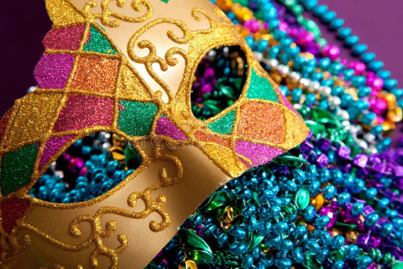 A background made up of a gold mardi gras mask and blue, purple, green and pink beads. A background made up of a gold mardi gras mask and blue, purple, green and pink beads