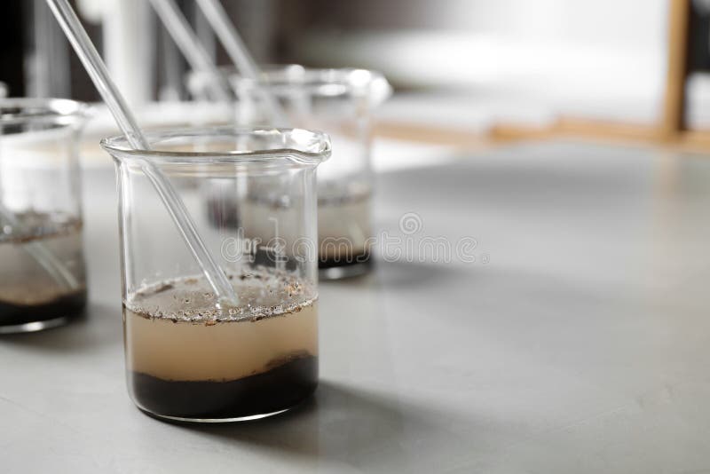 Beaker with soil extract on light table. Laboratory analysis