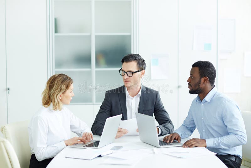 Beambten die bij bureau op vergadering zitten stock foto Beambten die bij bureau op vergadering zitten stock foto