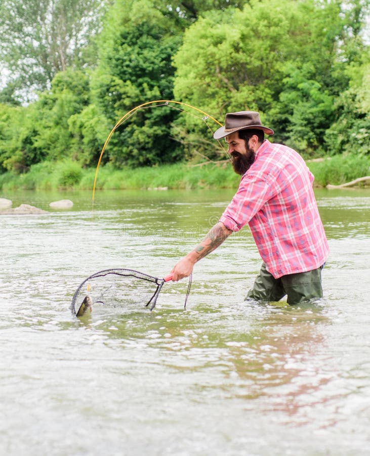 Bearded Brutal Fisher Catching Trout Fish With Net. Fishing Is An Astonishing Accessible Recreational Outdoor Sport