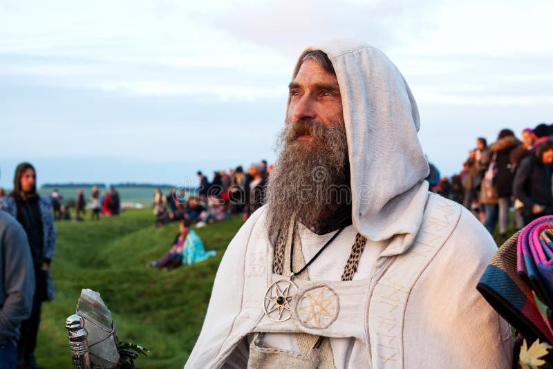 Bearded Druid in robes watches the sun rise at Stonehenge