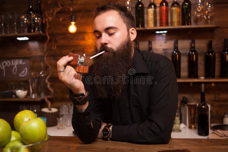 Bearded Handsome Young Bartender Lighting His Cigarette. Stock Image