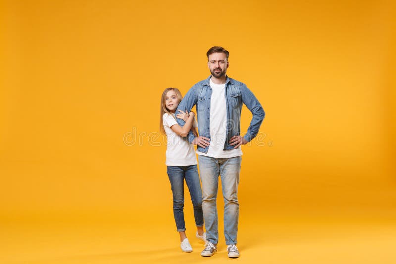 Bearded man in casual clothes with child baby girl. Father little kid daughter isolated on yellow background. Love family parenthood childhood concept. Stand with arms akimbo on waist holding hands