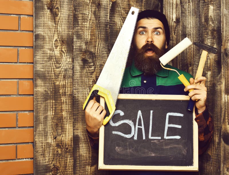 Bearded man holding various building tools and board, surprised face stock photography Bearded man holding various building tools and board, surprised face stock photography