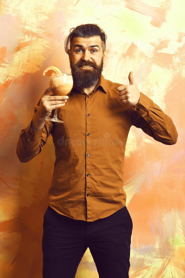 Brutal caucasian hipster holding tropical alcoholic fresh cocktail. Bearded man, long beard. Brutal caucasian smiling happy hipster with moustache in brown shirt stock photos Brutal caucasian hipster holding tropical alcoholic fresh cocktail. Bearded man, long beard. Brutal caucasian smiling happy hipster with moustache in brown shirt stock photos