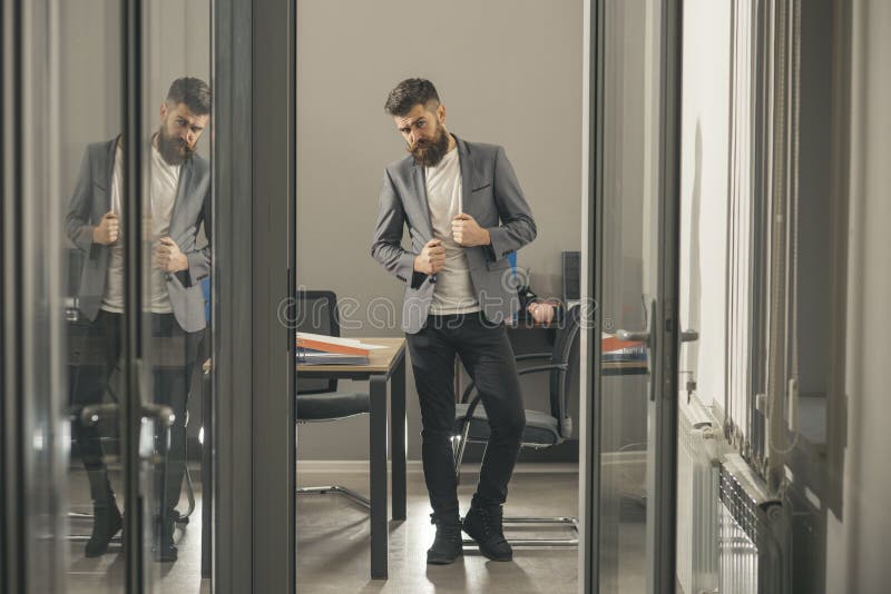 Bearded man look out office door. Bearded man in modern office with glass walls, business lifestyle royalty free stock image Bearded man look out office door. Bearded man in modern office with glass walls, business lifestyle royalty free stock image