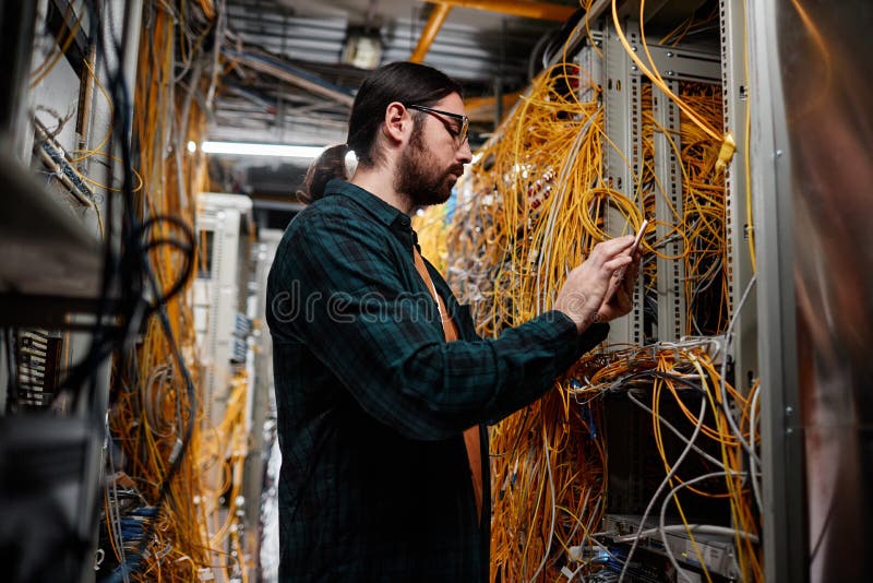 Bearded system administrator setting up network in server room royalty free stock photo