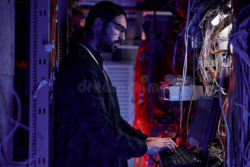 Bearded system administrator setting up server network in neon light royalty free stock image