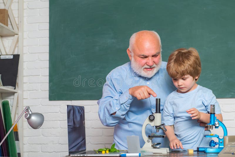 Bearded Teacher at school lesson at desks in classroom. World teachers day. Child from elementary school. Child pupil stock photo