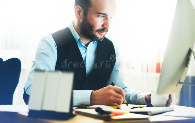 Bearded young businessman working on modern office. Consultant man thinking looking in monitor computer. Manager typing on keyboar stock photos