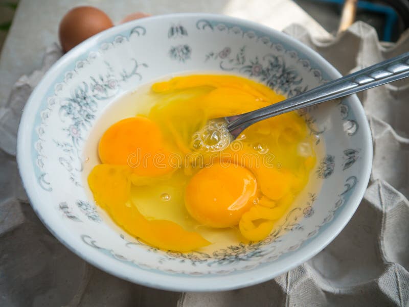 Beaten raw eggs with fork in bowl