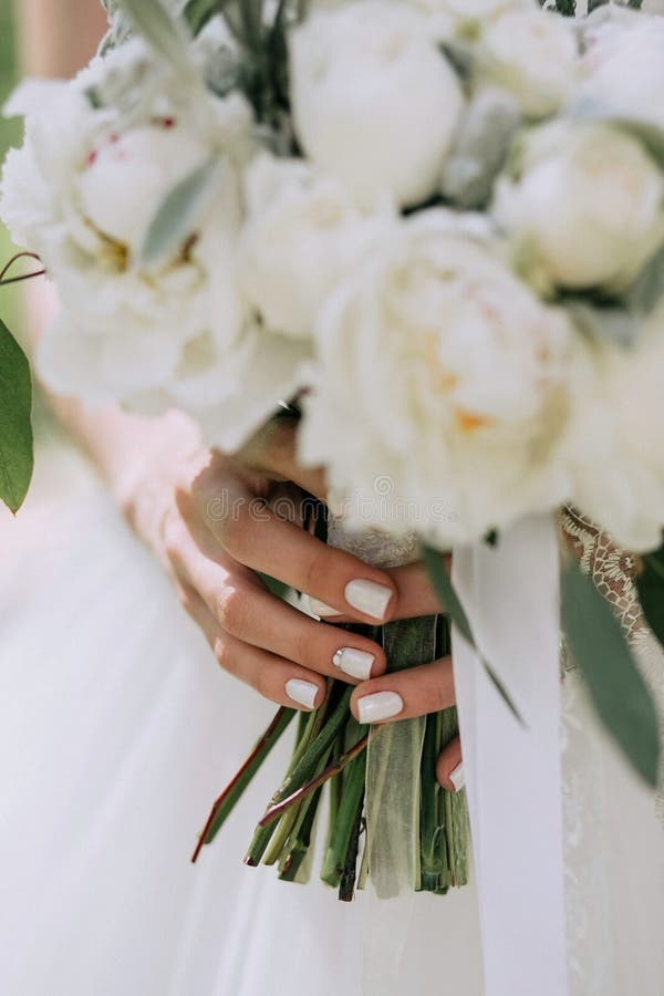 Beau bouquet élégant de mariage des pivoines blanches dans les mains de la jeune mariée avec une manucure élégante photos libres de droits Beau bouquet élégant de mariage des pivoines blanches dans les mains de la jeune mariée avec une manucure élégante photos libres de droits