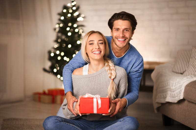 Beau couple avec cadeau devant l'arbre de noël photos stock