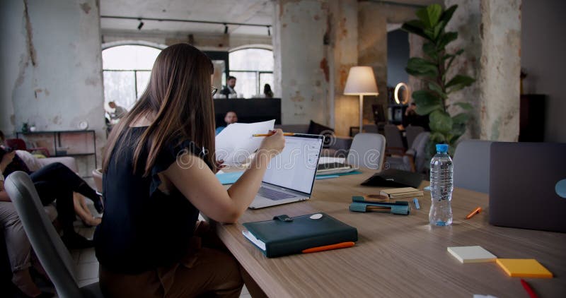 Beau jeune travailler caucasien sûr de femme d'affaires de vue latérale occupée avec des écrits au bureau léger moderne de grenier clips vidéos