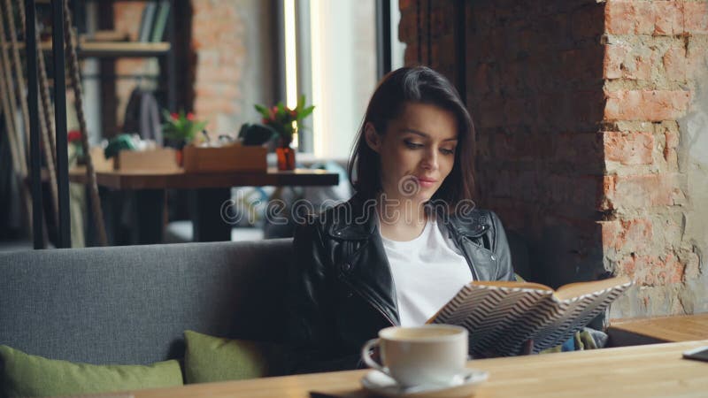 Beau livre de lecture de jeune dame en café appréciant la littérature et la solitude clips vidéos