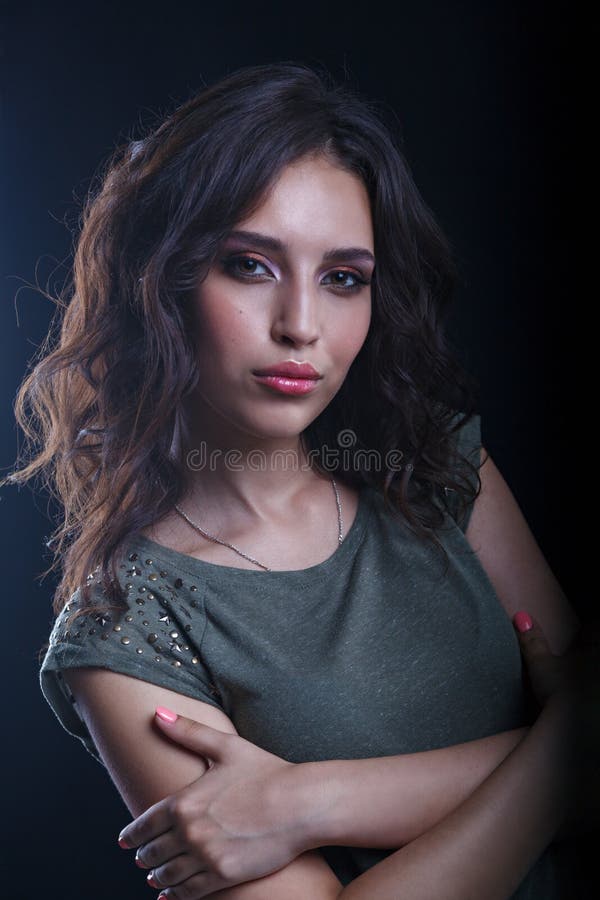 Beau modèle de brune de maquillage avec les cheveux bouclés semblant sexy sur un fond foncé Plan rapproché d'un portrait de femme images stock Beau modèle de brune de maquillage avec les cheveux bouclés semblant sexy sur un fond foncé Plan rapproché d'un portrait de femme images stock