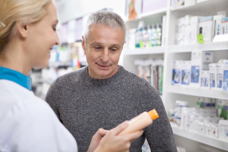 Beau pharmacien féminin aidant son client photo libre de droits Beau pharmacien féminin aidant son client photo libre de droits
