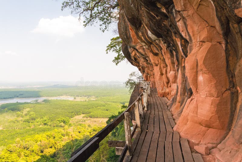 Beau pont en bois dans le cliffside rouge à la montagne de tok de Wat Phu photo libre de droits Beau pont en bois dans le cliffside rouge à la montagne de tok de Wat Phu photo libre de droits