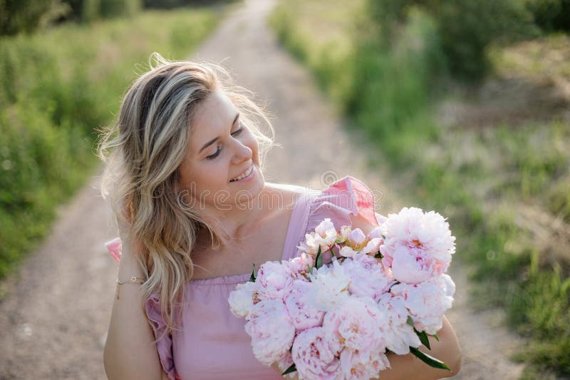 Beau portrait de femme heureuse dans la nature avec luxueux bouquet de pivoines le jour d'été. photo libre de droits