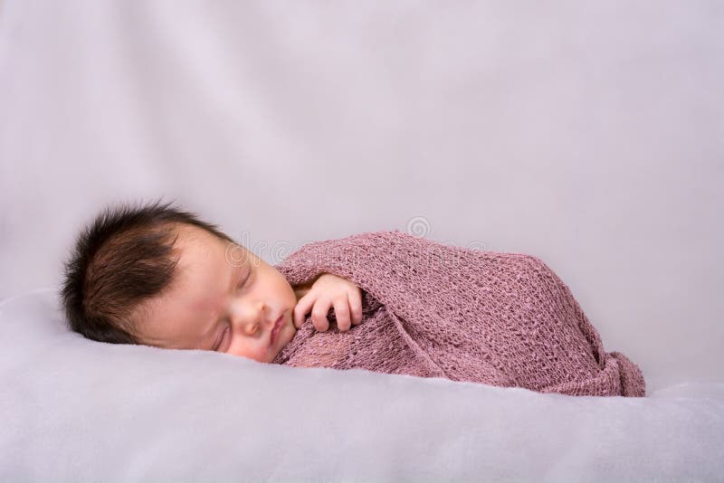 Beautiful newborn baby girl sleeping swaddled in a knit wrap. Beautiful newborn baby girl sleeping swaddled in a knit wrap