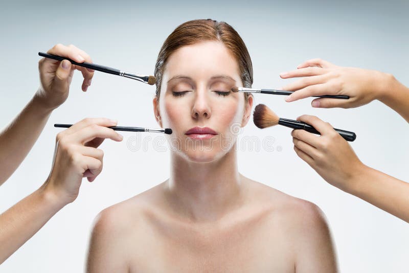 Beaucoup de mains s'appliquant le maquillage à la femme de charme au-dessus du fond blanc photos stock Beaucoup de mains s'appliquant le maquillage à la femme de charme au-dessus du fond blanc photos stock