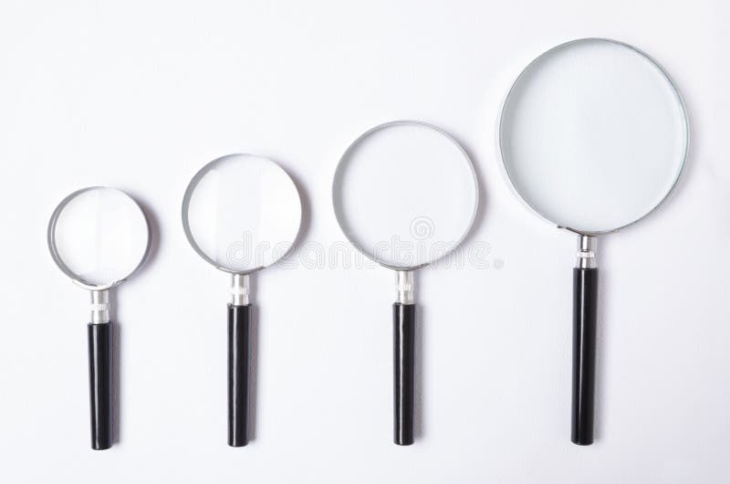 Set of magnifying glass with different power on white background,top view Many sizes of magnifying glass on white table,top view. Set of magnifying glass with different power on white background,top view Many sizes of magnifying glass on white table,top view